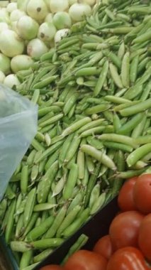 Bir adam bunları almak için pazardaki raftan yeşil bezelye seçiyor. Sağlıklı yemek..