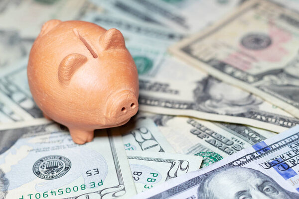 Керамическая копилка на пачке банкнот США, концепция сбережений и личных финансов. Финансовое планирование и домашняя экономика.
