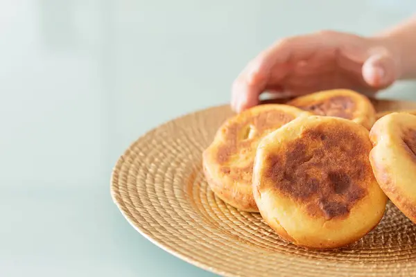 El yapımı bir tabakta nefis altın arepalar, bir el bir el alır. Yemek yemeye ve eğlenmeye hazır. Boşluğu Kopyala ile Resim.