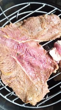 Izgarada bir parça çiğ et, bir fıçının içinde, bir adam kapağını kapatır..