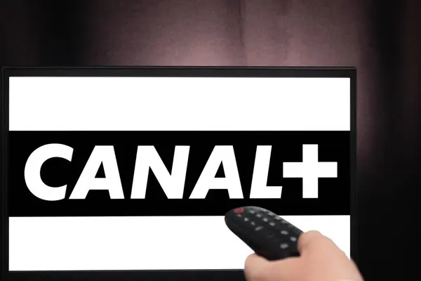 Bogota, Kolombiya - 14 Ocak 2025: Karanlık bir odada Canal + yansıtan bir televizyon ekranının önünde uzaktan kumandayı tutan bir el. Fransız Kanalı.