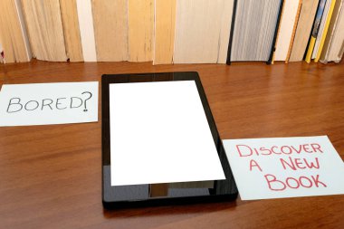 Boş ekranlı tablet - Sıkıcı mı? - Yeni bir kitap keşfedin -, arka planda bir satırda düzenlenmiş bazı kitaplar var.