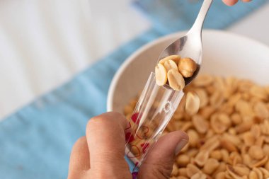 Küçük porsiyonlarda tuzlu fıstık paketleme işlemi. Eller kaşığın yardımıyla bir torbaya fıstık koyuyor.