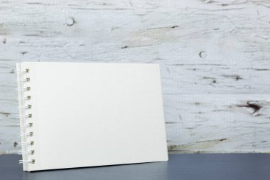 Beyaz ahşap arka plan önündeki masada yatay çizim defteri, yaratıcılık kavramına sahip minimalist ve nötr sahne