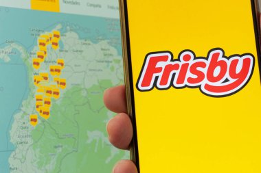 Bogota, Kolombiya - 14 Mayıs 2025. Frisby logosunu arka planda Kolombiya haritası olan cep telefonunda gösteren kişi, marka tartışmaları sırasında zincirin ülkedeki kapsamına işaret ediyor.