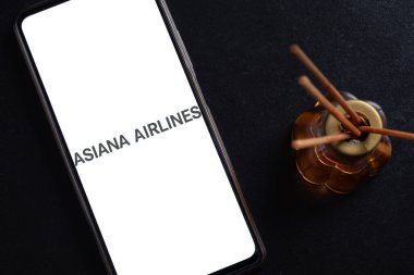 Bogota, Kolombiya - 13 Mayıs 2025: Asiana Havayolları 'nın logosu, Güney Kore havayolları, cep telefonu ekranında desenli siyah bir arka planda aromatik bir hava spreyinin yanında.
