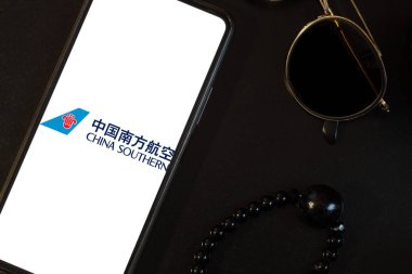 Bogota, Kolombiya - 13 Mayıs 2025: China Southern Airlines, Çin Havayolları, siyah arka planda, gözlük ve boncuklu kolyenin yanında. Seyahat kavramı
