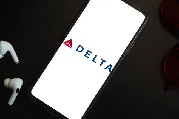 Bogota, Kolombiya - 13 Mayıs 2025: Delta Hava Yolları, ABD Havayolları, cep telefonu ekranında, kablosuz kulaklıklar ve profesyonel karanlık arka planda gözlüklerle