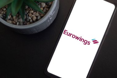 Bogota, Kolombiya - 13 Mayıs 2025: Eurowings, Almanya havayolu, cep telefonuyla seyahat sahnesi için sulu saksı bitkisinin yanında. Turizm konsepti