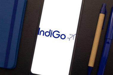 Bogota, Kolombiya - 13 Mayıs 2025: Hindistan 'ın düşük maliyetli havayolu şirketi Indigo' nun logosuyla cep telefonu, ekolojik defter ve kalemlerle birlikte, sürdürülebilir seyahati bağlayan yaratıcı görüntü
