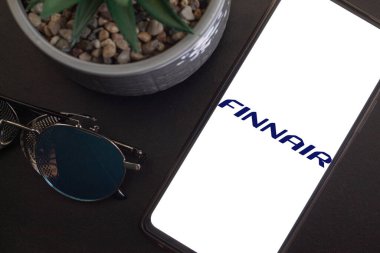 Bogota, Kolombiya - 13 Mayıs 2025: Finnair, Finlandiya 'dan havayolu şirketi, cep telefonuyla koyu gözlüklerin yanında ve ayık ve zarif bir ortamda bitki süsleme