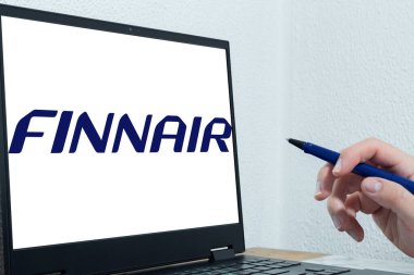 Bogota, Kolombiya - 14 Mayıs 2025: Finnair, Finlandiya 'nın bayrak taşıyıcısı, elinde kalem olan bir kişinin önünde dizüstü bilgisayara yansıtıldı. Uluslararası hava yolculuğu