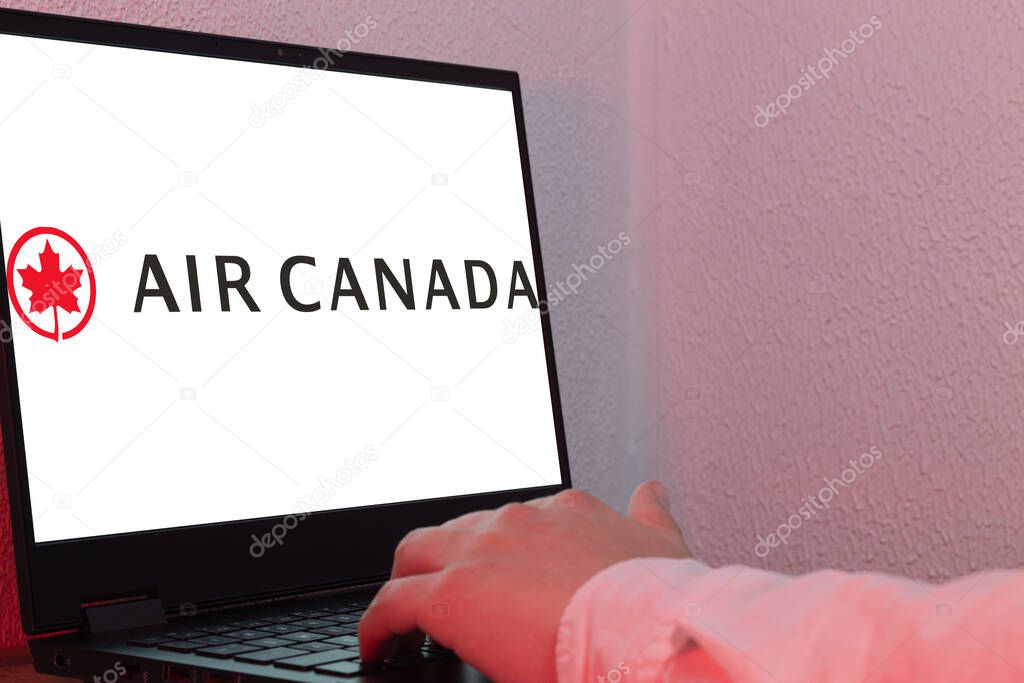 Bogota, Colombia - May 14, 2025: Laptop showing the logo of Air Canada, Canada's national airline, on light background with hand pointing to screen, image for corporate travel content
