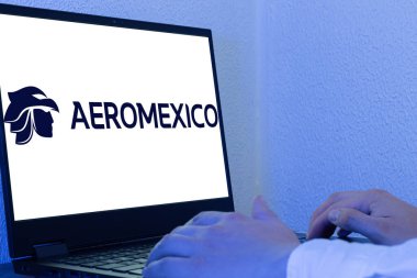Bogota, Kolombiya - 14 Mayıs 2025: Meksika 'nın önde gelen havayolu şirketi Aeromexico' yu gösteren dizüstü bilgisayar, mavi ışıklı bir ortamda, erkek eli seyre hazır, online rezervasyon kavramı