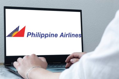 Bogota, Kolombiya - 14 Mayıs 2025: Filipinler ulusal havayolu şirketi Filipin Havayolları 'nın logosu olan bir dizüstü bilgisayarın klavyesinde yazan kişi. İnternetten bilet almak