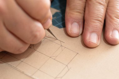 Minyatür bir karton kutunun şablonunu kesmek için neşter kullanan biri. DIY ambalaj, markalaşma ve e-ticaret için planlama ve ölçümler