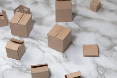 Minyatür karton kutular hasırın üzerinde ve beyaz mermer bir masanın üzerinde.