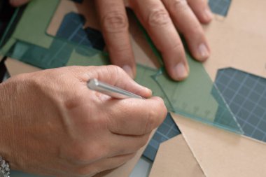 Yetişkin ellerinin kartondan bıçak kesmesi ve paspas üzerinde kare kesmesi, modeller, ambalaj ve okul projeleri için güvenli bir teknik.