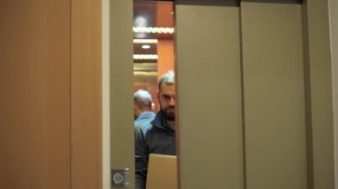 Asansörden inen teslimatçı elinde bir paket taşıyordu..