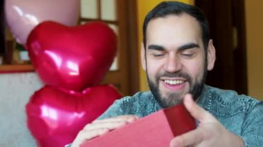 Young bearded man receiving a red box gift during valentine's day