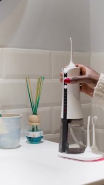 Young woman hands changing his domestic dental water flosser tip 4K vertical video