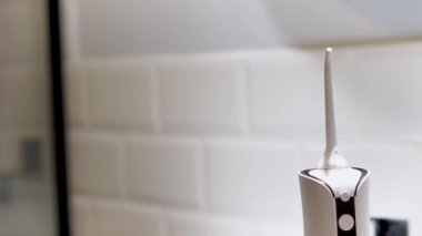Dentist's hand showing how to use domestic dental water flosser for a deep cleaning at home
