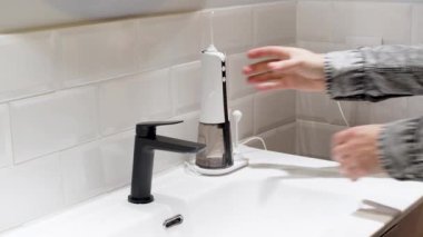 Effortless Oral Health: man Filling Water Flosser Tank at Bathroom Basin