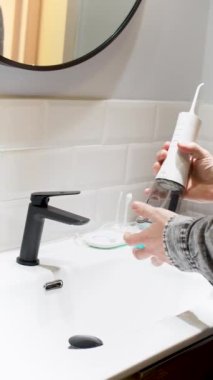  Çabasız Ağız Sağlığı: Su Flosser Tankını Banyo Havzası 4K dikey videosunda ağız gargarasıyla dolduran adam