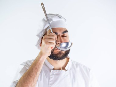 Metal kepçe kullanan genç bir aşçı. Beyaz bir arkaplanda izole edilmiş