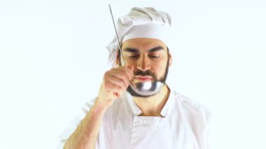  Metal kepçe kullanan genç bir aşçı. Beyaz bir arkaplanda izole edilmiş