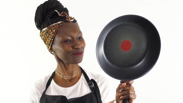 年轻的女厨师笑着展示并指着一个不粘的平底锅 被白色背景隔离 — 图库视频影像