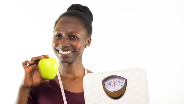体重計を持っている若い女性と白い背景に隔離された緑のリンゴ — ストック動画