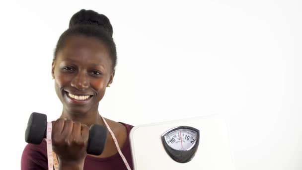 Mujer Joven Mostrando Una Escala Peso Mientras Levanta Una Mancuerna — Vídeo de stock