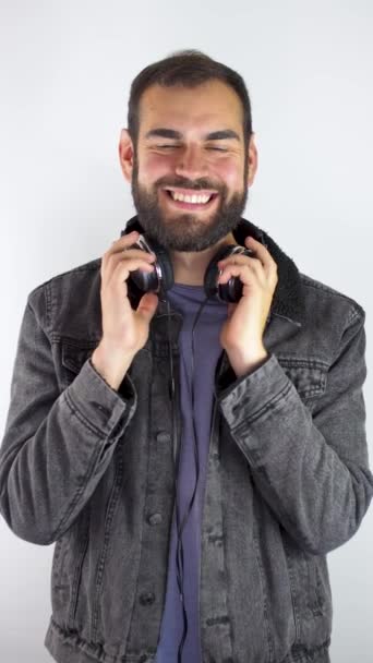 白い背景に隔離された笑顔でヘッドフォンを使用している若い男垂直ビデオ — ストック動画