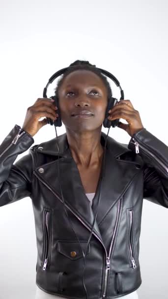 白い背景にビニール製のロングプレイレコードを見せながらヘッドフォンを使用している若い女性 垂直ビデオ4K — ストック動画
