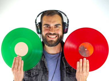 Genç adam beyaz arka planda kırmızı ve yeşil vinyleri tutuyor ve karşılaştırıyor.