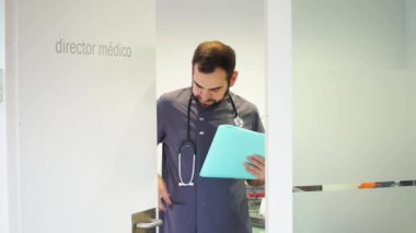 Ofisinde elinde bir dosya tutan genç bir dişçi var.