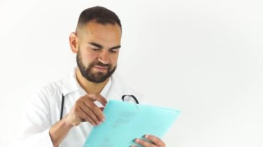 Genç bir erkek doktor bir dosyanın üzerine kalemle yazıyor. Beyaz arkaplanda izole