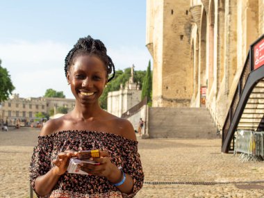Genç ve güzel bir kadın, Avignon 'un tarihi bir yerinde dururken daktilo yazıyor.