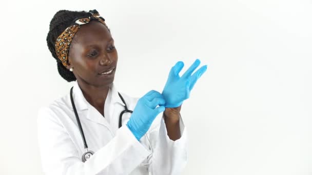白い背景に隔離された彼女の手袋を置く若い女性の医師 — ストック動画