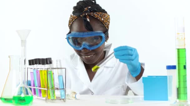 テスト管の2つの液体サンプルを比較する保護眼鏡を身に着けている若い女性科学者 — ストック動画