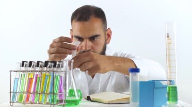 Laboratuvarda genç bir bilim adamı ölçüm silindirinden bir beher şişesine sıvı örneği döküyor.