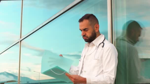 Молодий Чоловік Лікар Страждає Стресом Тривогою Дивлячись Документи Перед Лікарнею — стокове відео