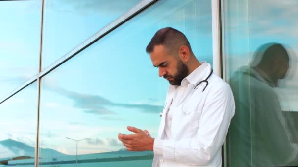 Młody Mężczyzna Lekarz Wpisując Telefonie Przed Szpitalem — Wideo stockowe