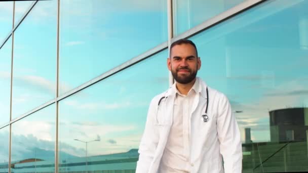 Genç Bir Erkek Doktor Hastanenin Önünde Kameraya Bakarken Kollarını Kavuşturuyor — Stok video