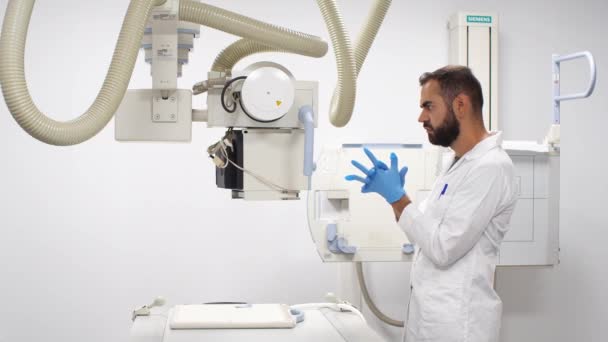 X線機を使用する前に青いラテックス手袋を持っている若い男性医師 — ストック動画