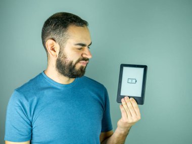 Genç sakallı adam elinde pil olmadan elektronik bir kitap tutuyor.