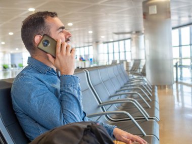 Bearded man using his smarphone while waiting in the airport terminal