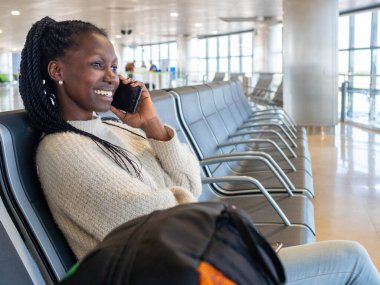 A young woman using her phone while waiting for her flight in the airport lounge
