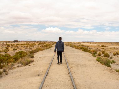 Uyuni Bolivya 'da terk edilmiş bir demiryolunda yürüyen bir gezgin.
